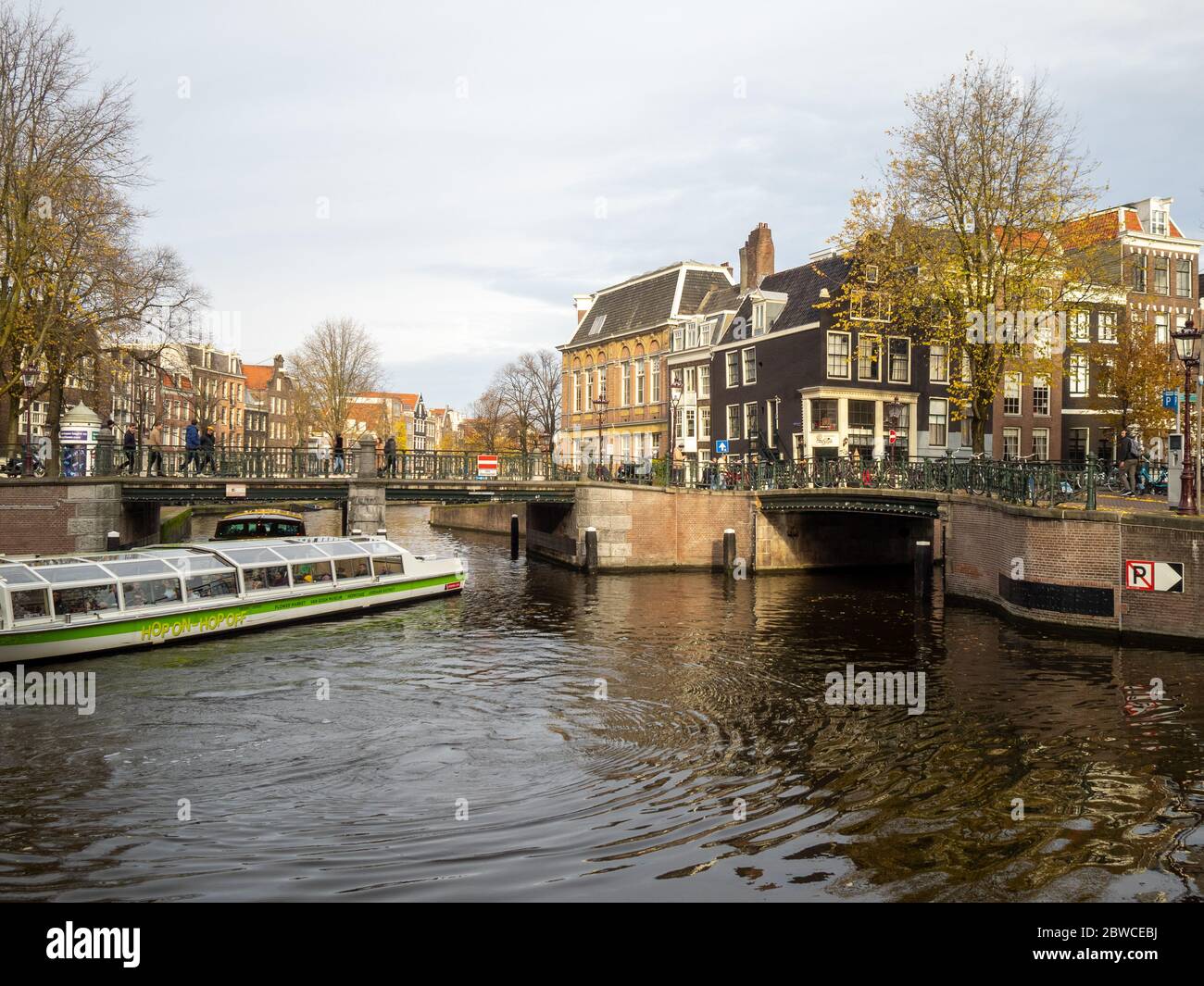 Barca turistica che manovrano i canali di Amsterdam Foto Stock