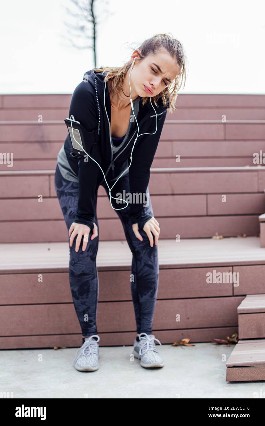 Stanca giovane donna che riposa dopo aver fatto jogging all'aperto Foto Stock