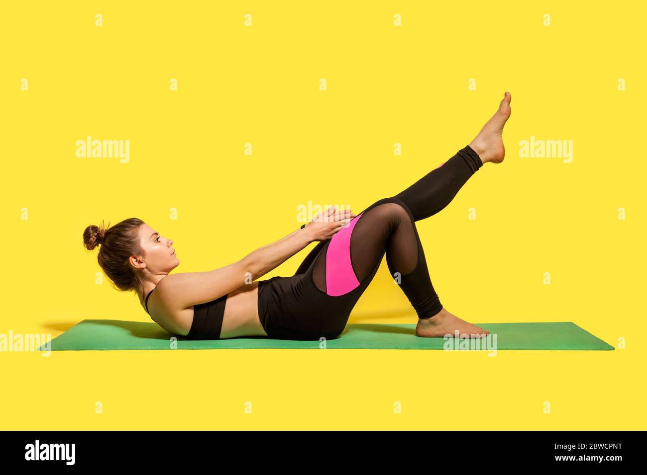 Donna fitness motivata con capelli bun in yoga pantaloni allenamento su palestra tappetino, raggiungendo le mani ai piedi stretching muscoli, riscaldamento con flessibilità exerci Foto Stock