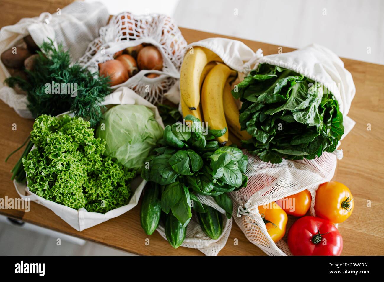 Verdure fresche e frutta in sacchetti riutilizzabili di cotone eco sul tavolo in cucina. Concetto di shopping senza sprechi. Vita sostenibile Foto Stock