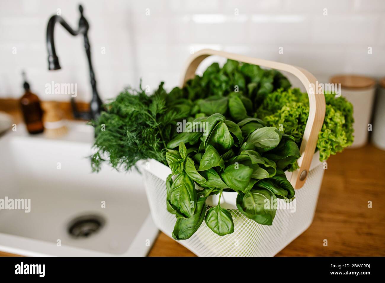 Insalate fresche ed erbe in cesto di metallo sul tavolo in cucina. Concetto di shopping senza sprechi. Vita sostenibile Foto Stock