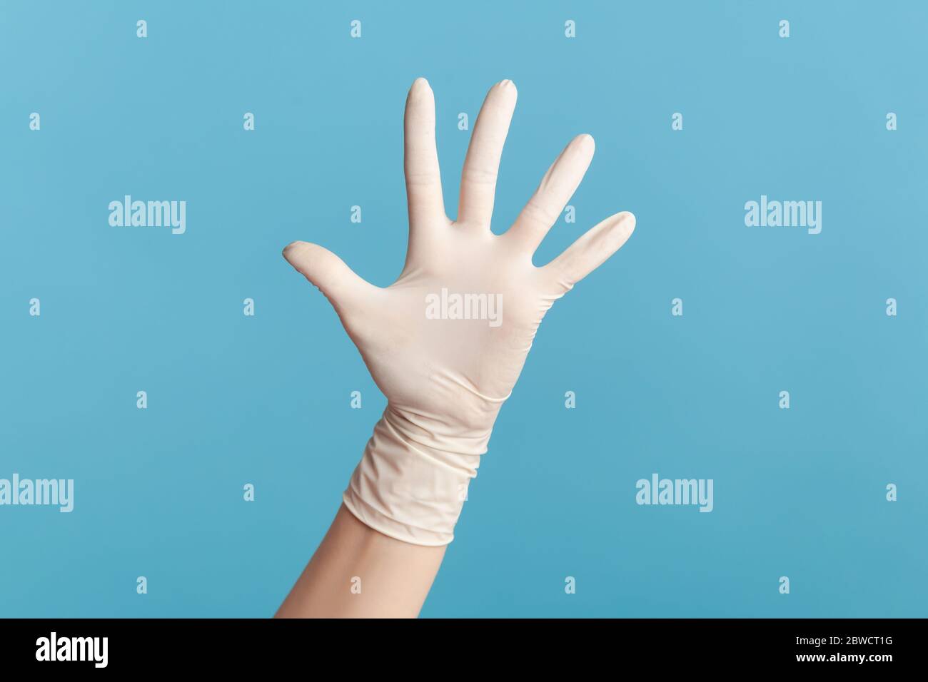 Profilo Vista laterale primo piano della mano umana in guanti chirurgici bianchi che mostrano il numero cinque con la mano o con la mano che ondola al saluto. Interno, studio shot, isolat Foto Stock