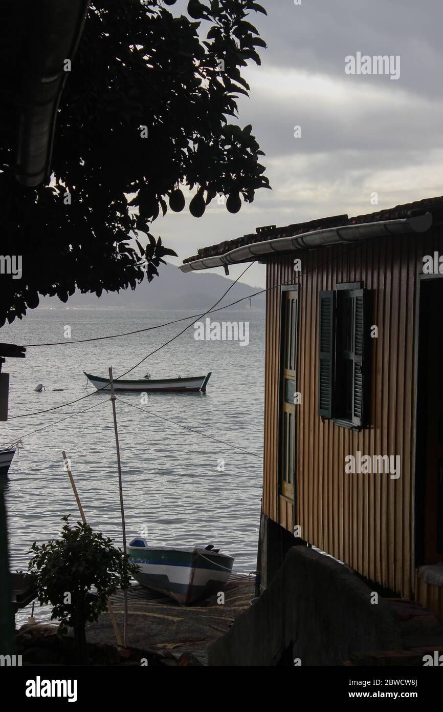 Una casa a fianco smussato clasica con una barca parcheggiata sulla riva in una giornata di clam e nuvoloso. Foto Stock