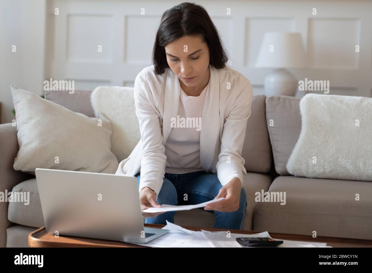 La giovane donna pensiva gestisce le finanze domestiche della famiglia Foto Stock