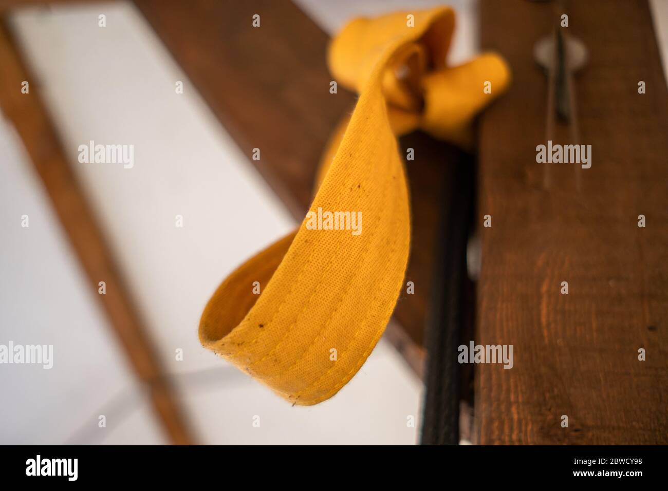 Vista ad angolo ridotto del nastro giallo del carato annodato alla trave in legno Foto Stock