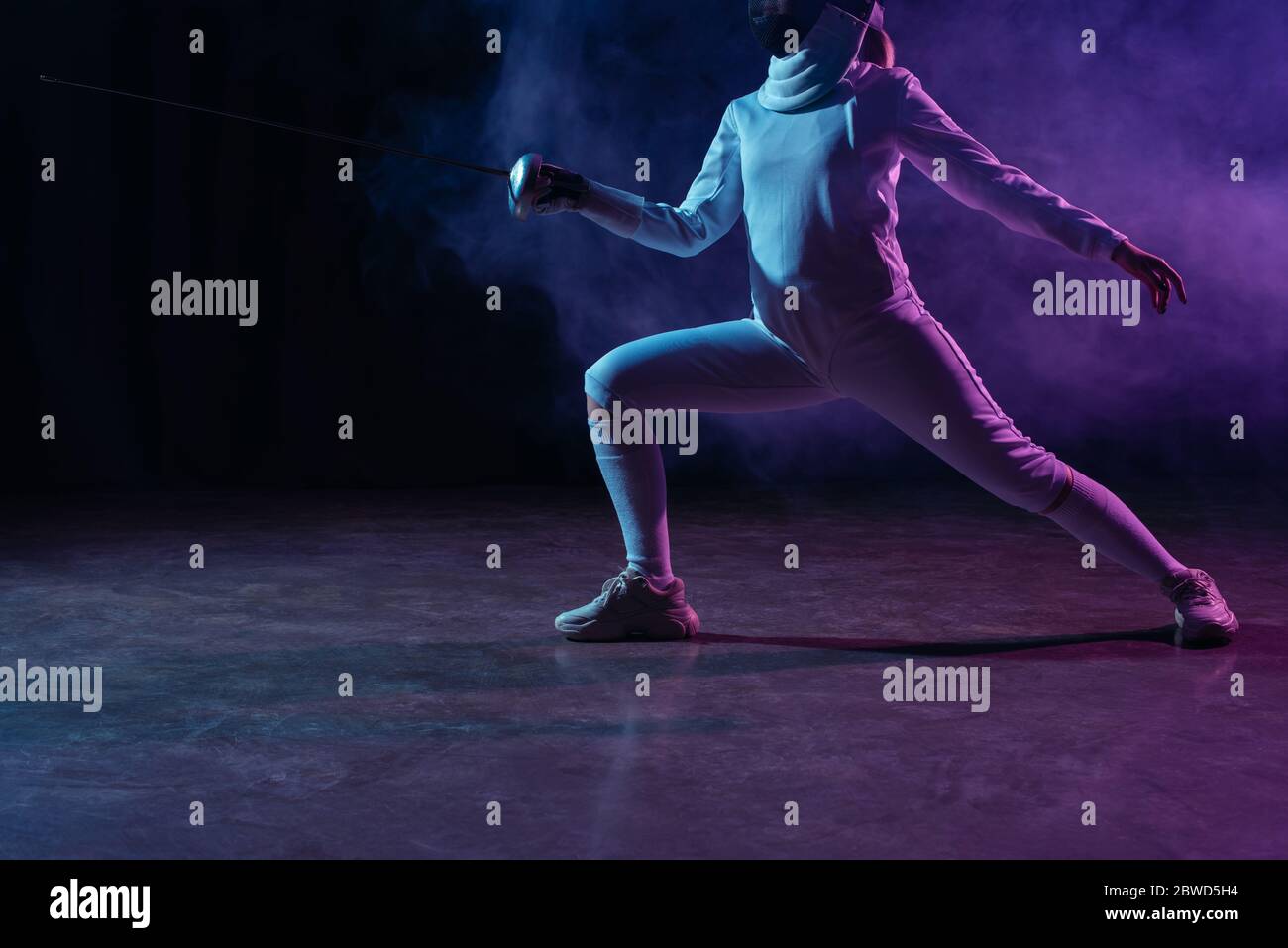 Vista ritagliata della scherma della spada su sfondo nero con fumo e illuminazione Foto Stock