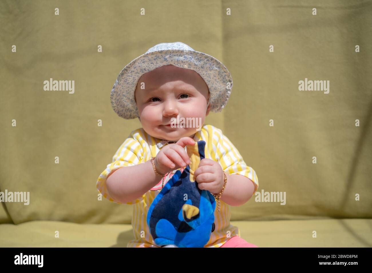 Cute baby girl indossare adorabile cappello guardando la macchina fotografica rendere divertenti volti su sfondo verde Foto Stock