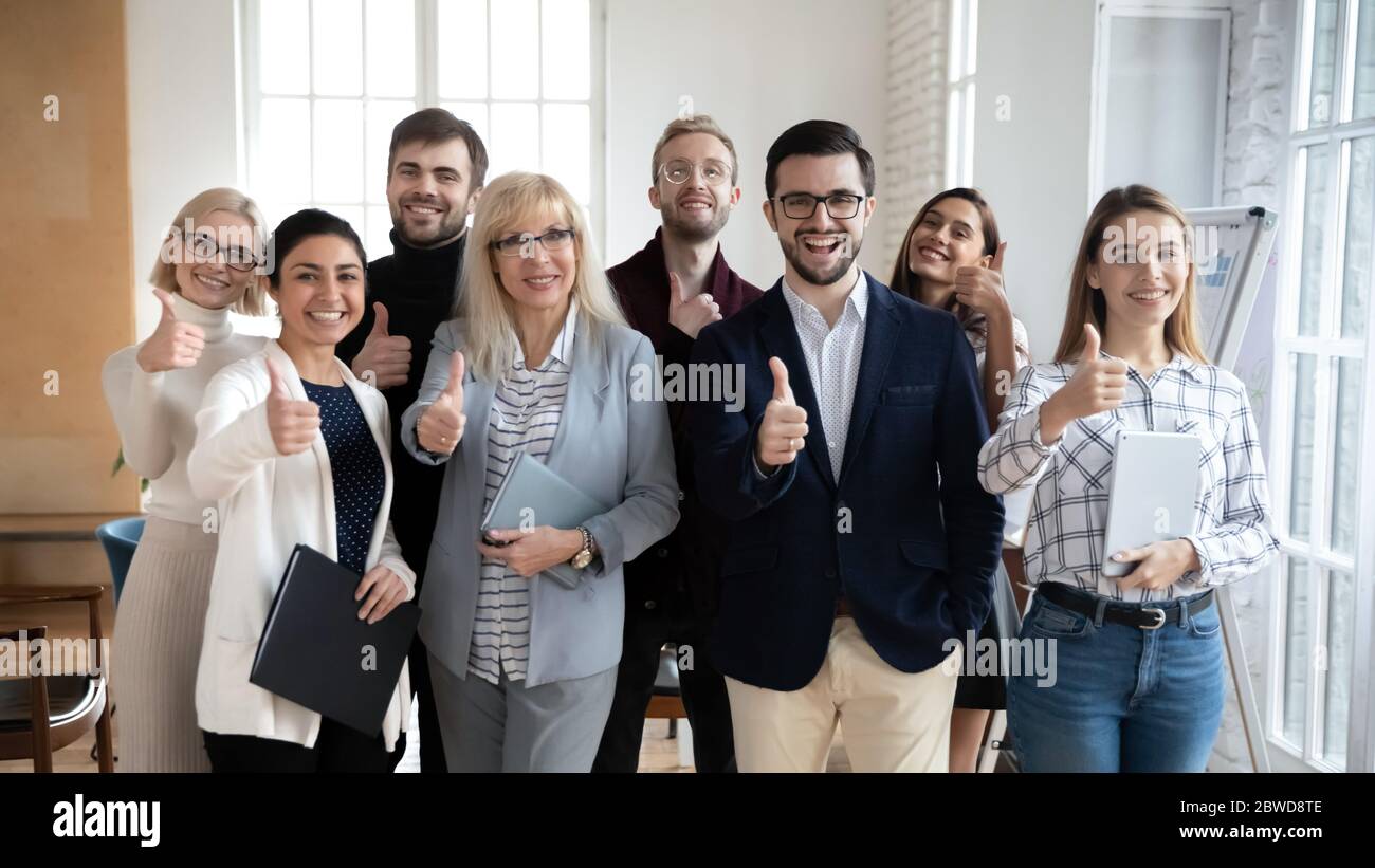 Gruppo entusiasta di uomini d'affari diversi che mostrano i pollici verso l'alto gesto. Foto Stock