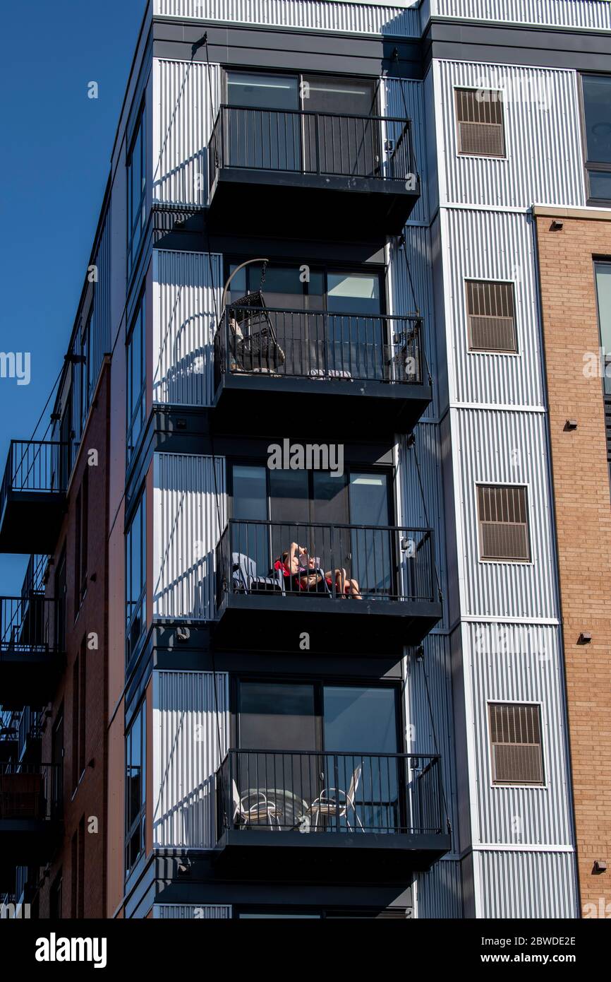 St. Paul, Minnesota. Una donna si rilassa sul suo patio da sola a causa della distanza sociale e la pandemia del coronavirus Foto Stock
