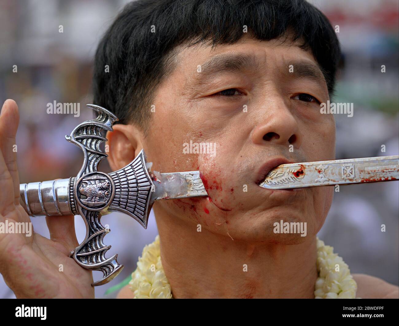 Il devoto taoista cinese tailandese pierces la sua guancia destra con una spada tradizionale durante il Festival vegetariano di Phuket (Nine Emperor dei Festival). Foto Stock