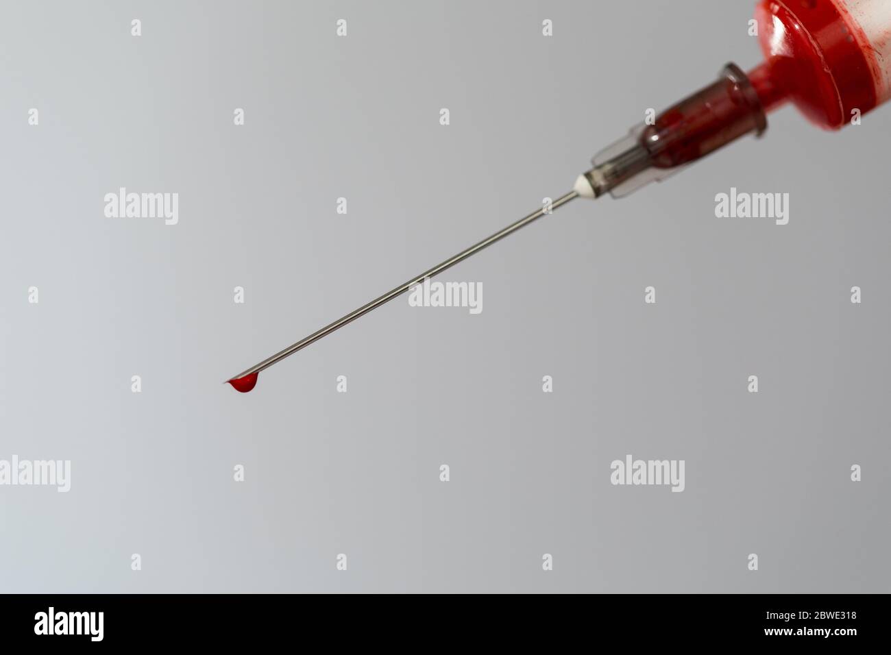 Siringa con un campione di sangue. Una goccia di sangue all'estremità dell'ago. Chimica del sangue. Analisi del sangue per virus. Foto Stock