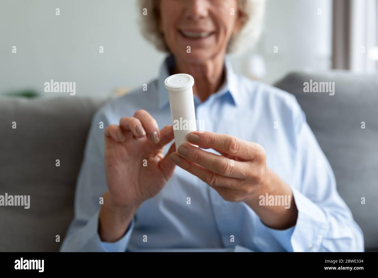 Primo piano su vecchie mani femminili che tengono confezione di plastica con pillole Foto Stock