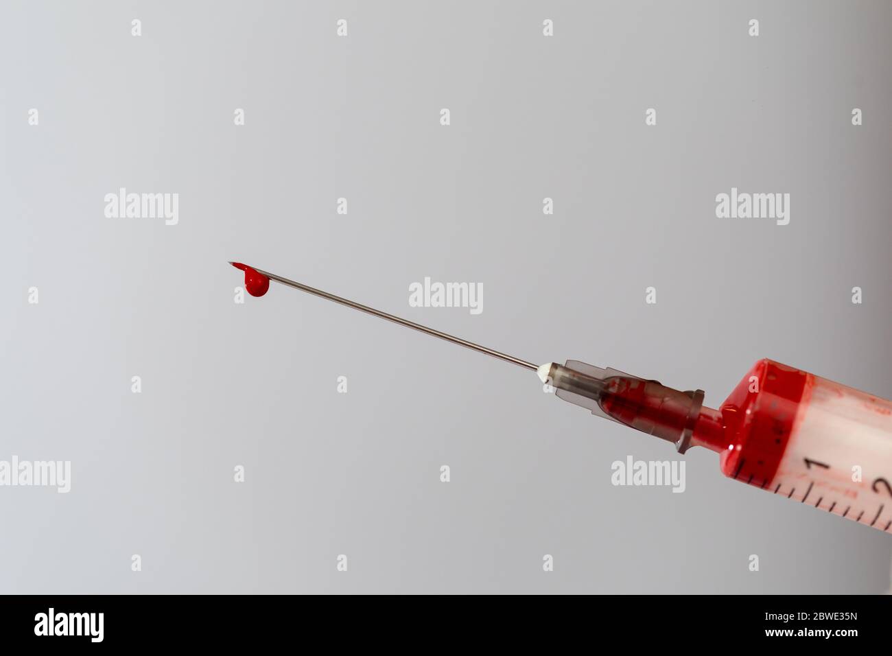 Siringa con un campione di sangue. Una goccia di sangue all'estremità dell'ago. Chimica del sangue. Analisi del sangue per virus. Foto Stock