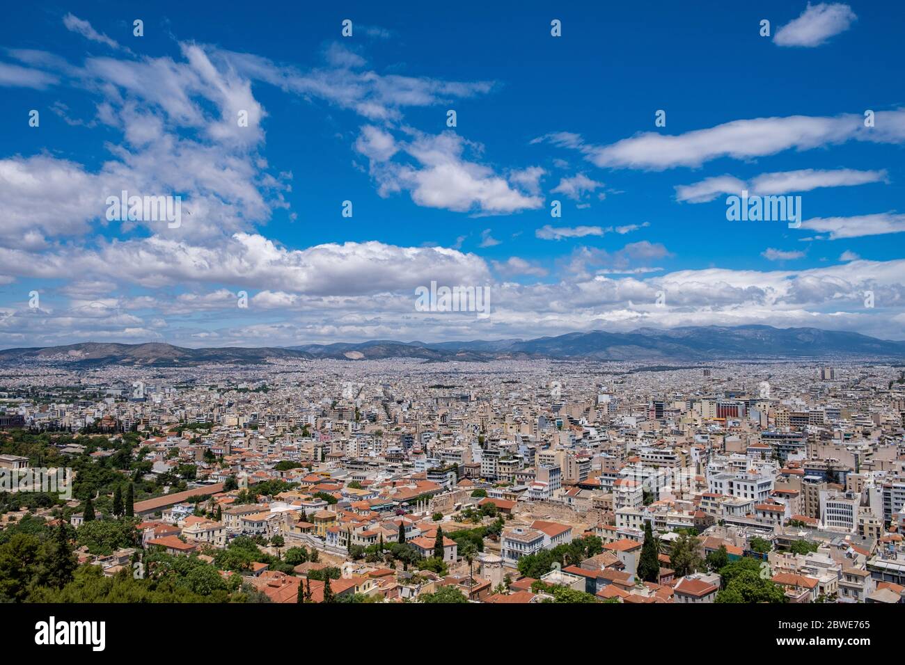 Atene contro il cielo blu nuvoloso in una giornata di primavera. Vista aerea dalla collina dell'Acropoli. ATTICA, Grecia Foto Stock