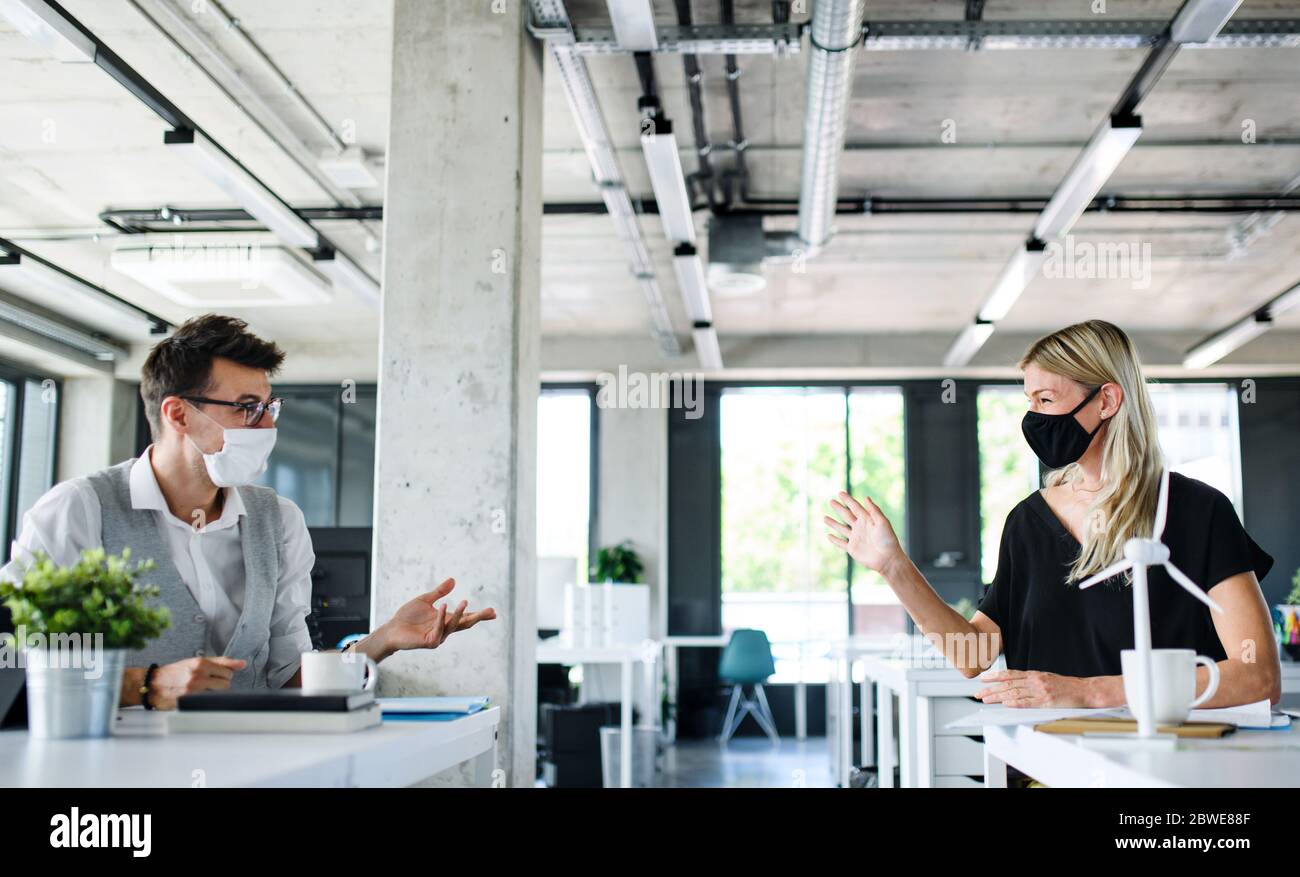 I giovani con maschere facciali tornano al lavoro dopo il blocco. Foto Stock