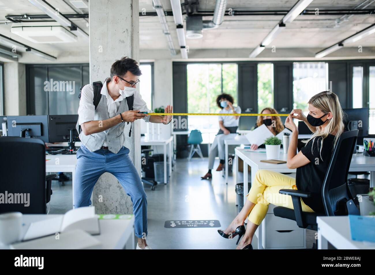 I giovani con maschere facciali tornano al lavoro dopo il blocco, misurando la distanza. Foto Stock