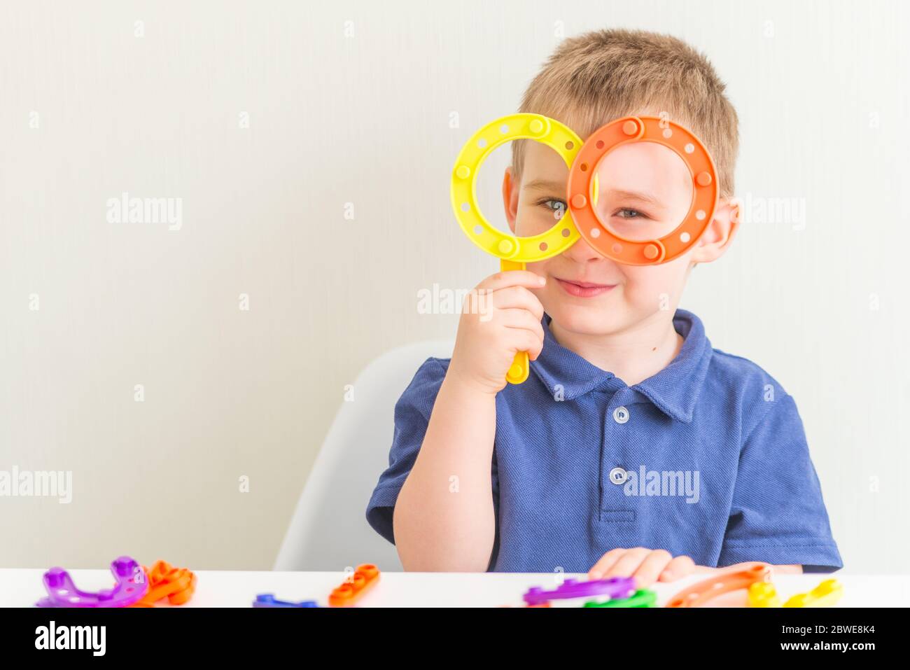 Adorabile ragazzo fatto bicchieri di plastica blocco giocattolo e sorridente.Copy spazio. Foto orizzontale di divertente bimbo Foto Stock