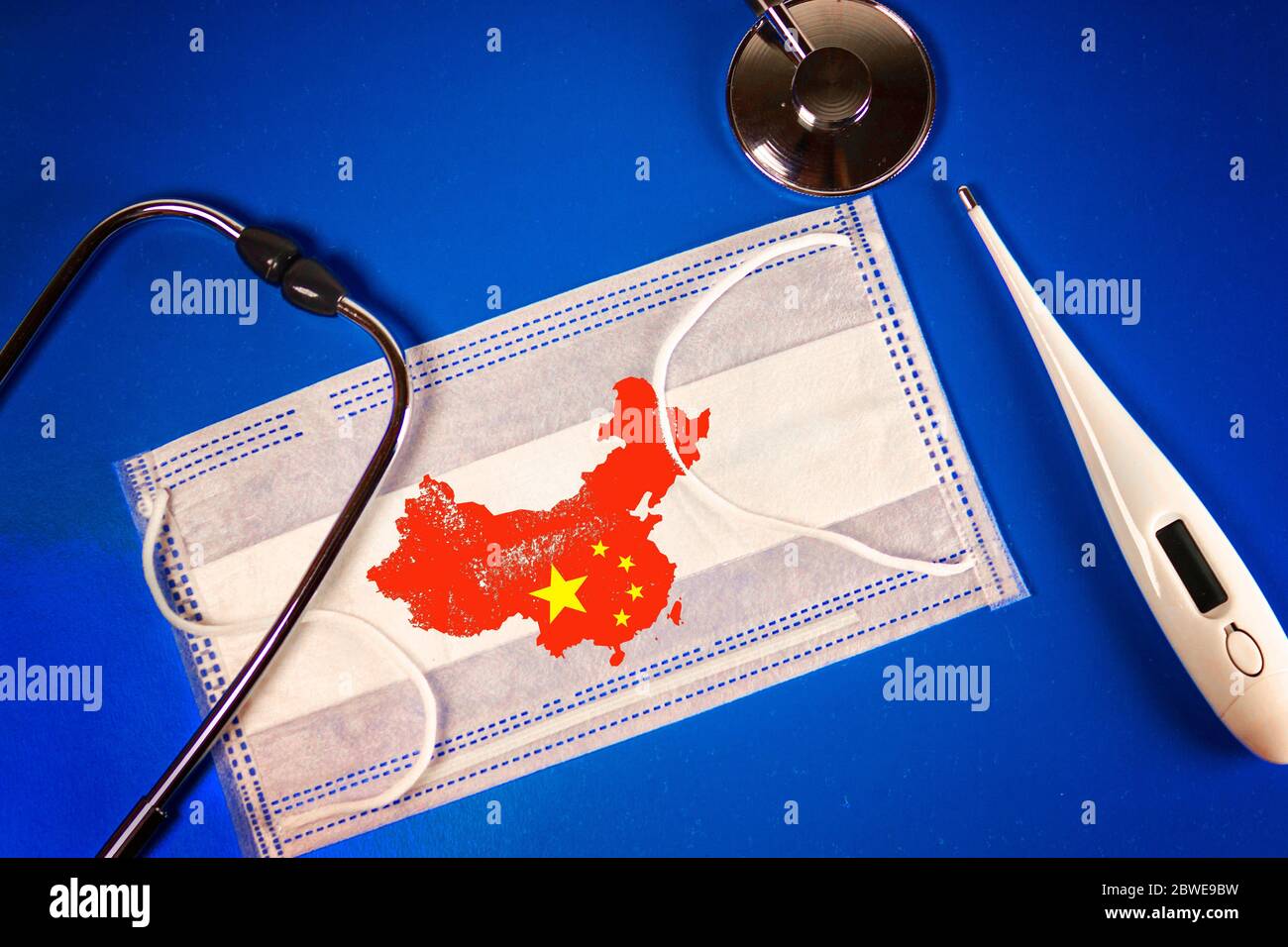 Stetoscopio, termometro e termometro maschera medica con la Repubblica popolare cinese mappa paese silhouette e un timbro: 2019-nCoV, su uno sfondo blu Foto Stock