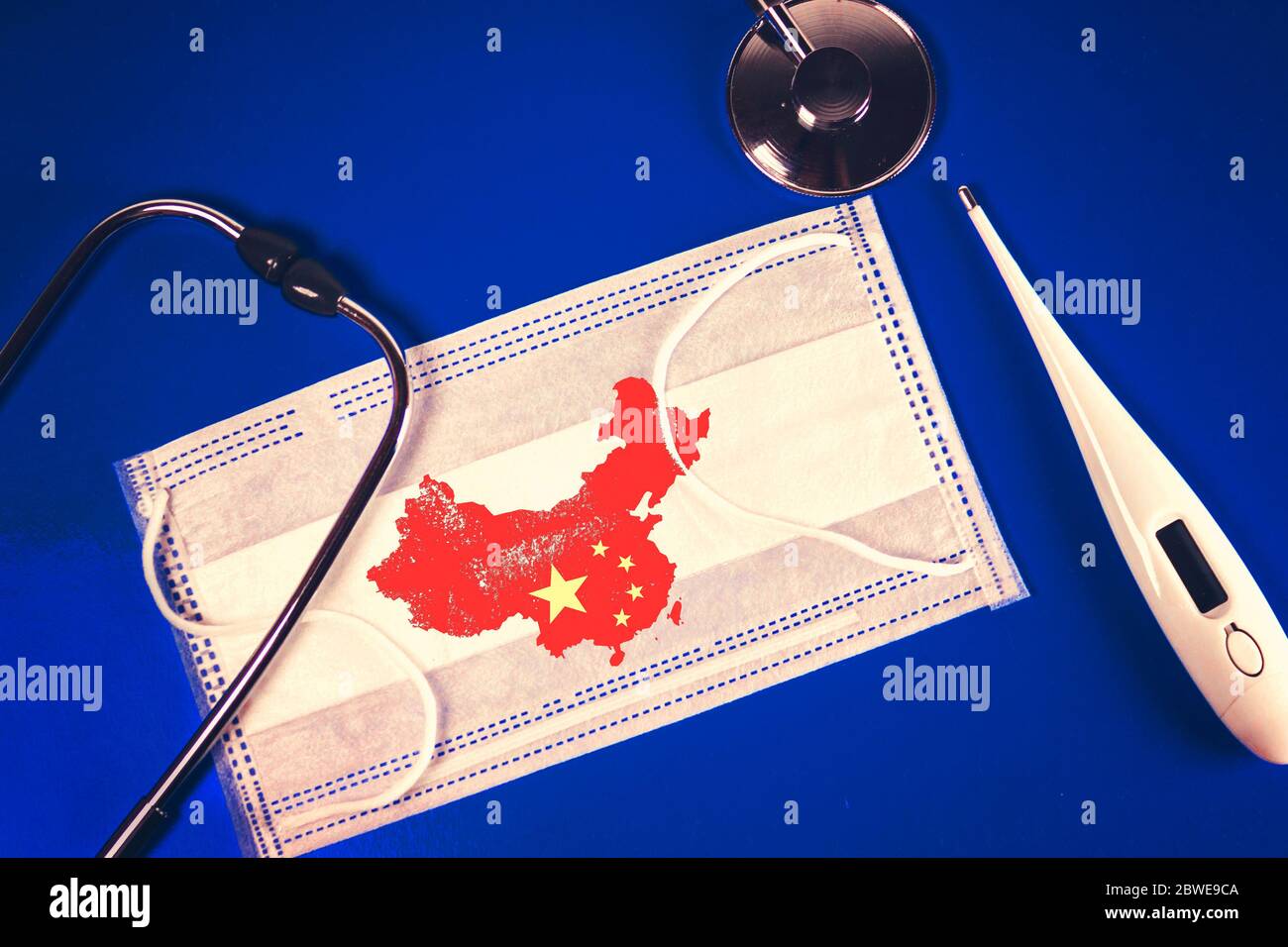 Stetoscopio, termometro e termometro maschera medica con la Repubblica popolare cinese mappa paese silhouette e un timbro: 2019-nCoV, su uno sfondo blu Foto Stock