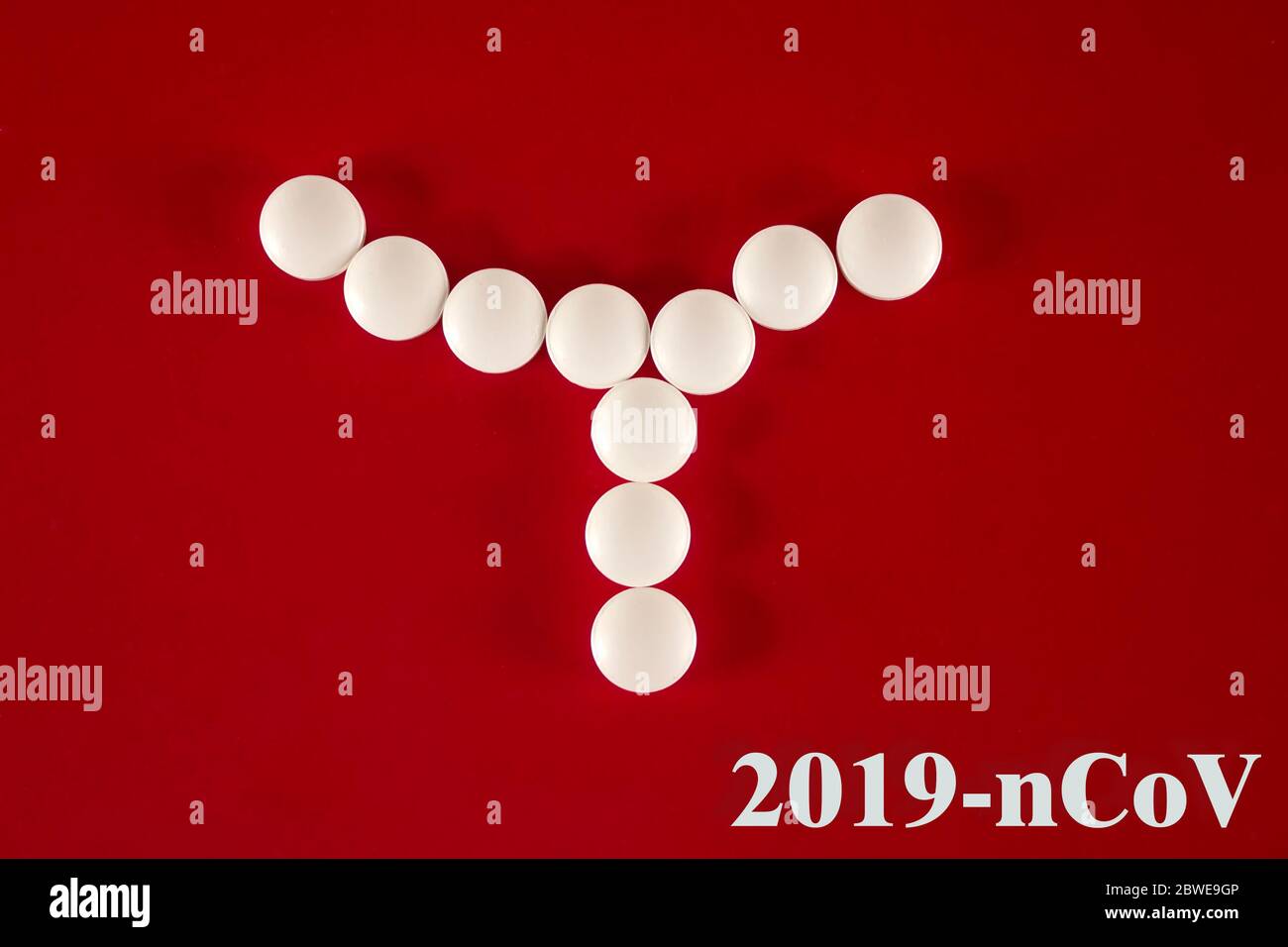 Cellula batterica composta da compresse bianche con l'iscrizione 2019 nCoV su sfondo rosso, vista dall'alto. 2019 nuovo Coronavirus 2019-nCoV concetto. Foto Stock