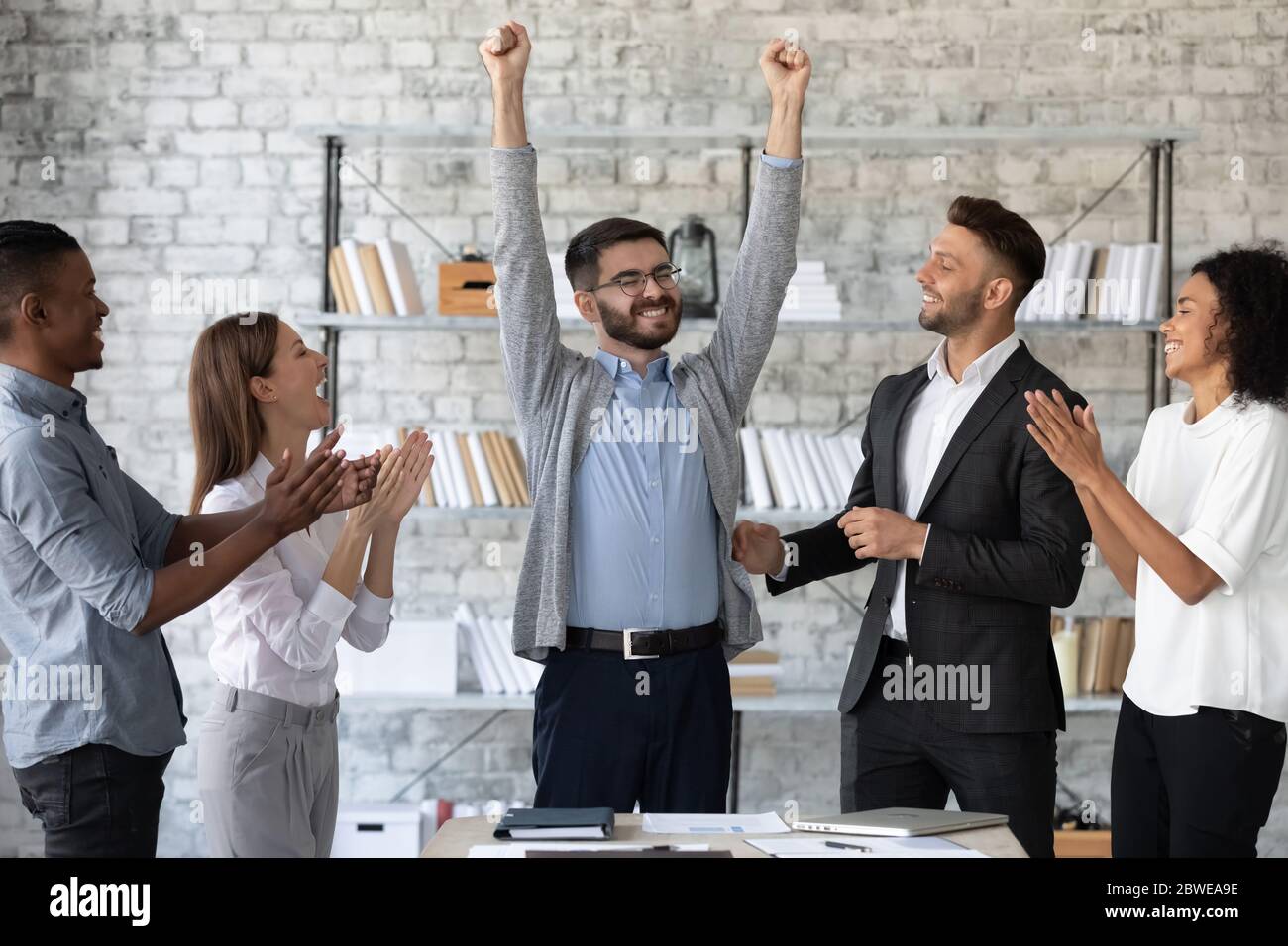 Dipendenti diversi che si congratulano con un collega di successo con la promozione Foto Stock