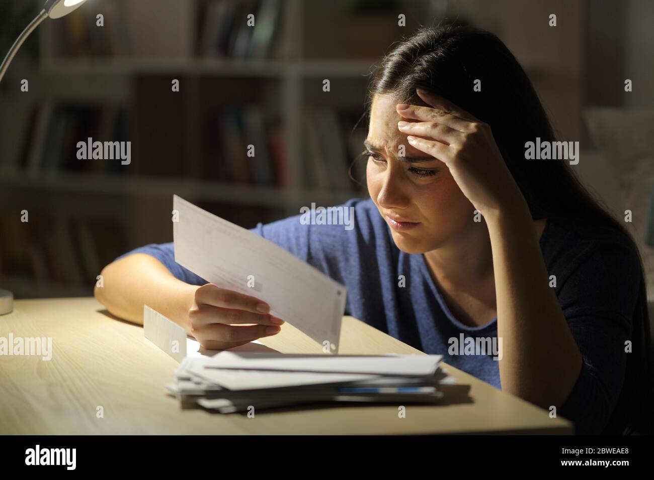 Donna preoccupata che guarda le ricevute di notte seduto nel soggiorno a casa Foto Stock