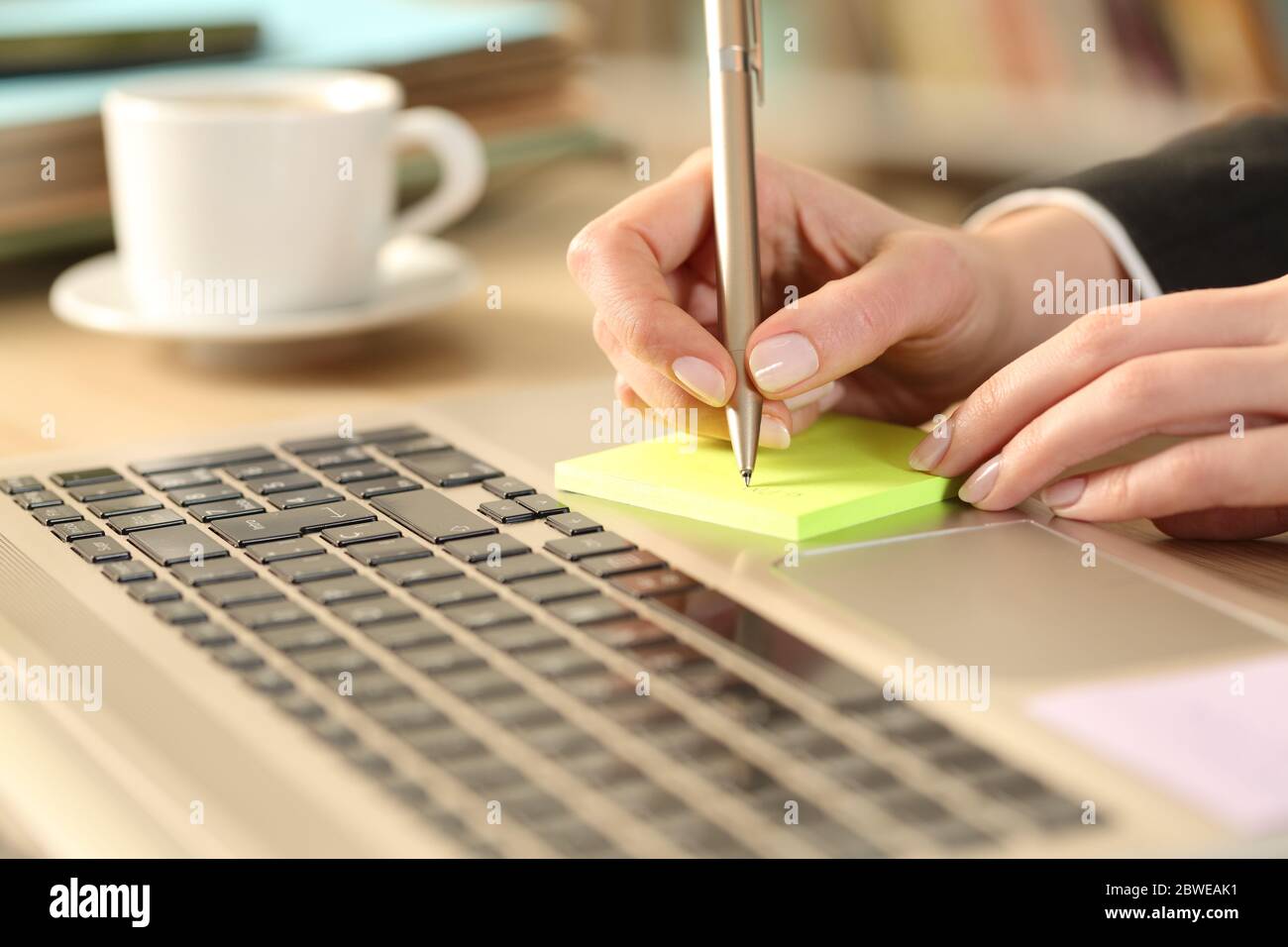 Primo piano di donna imprenditore mani che scrivono promemoria su post nota su una scrivania a casa Foto Stock