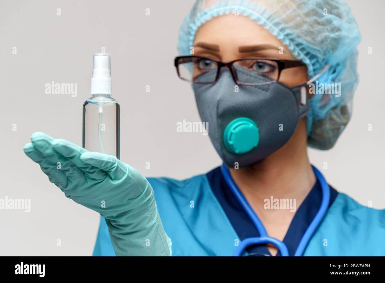 medico medico infermiere che indossa la maschera protettiva - contenente il flacone di spray o gel igienizzante Foto Stock