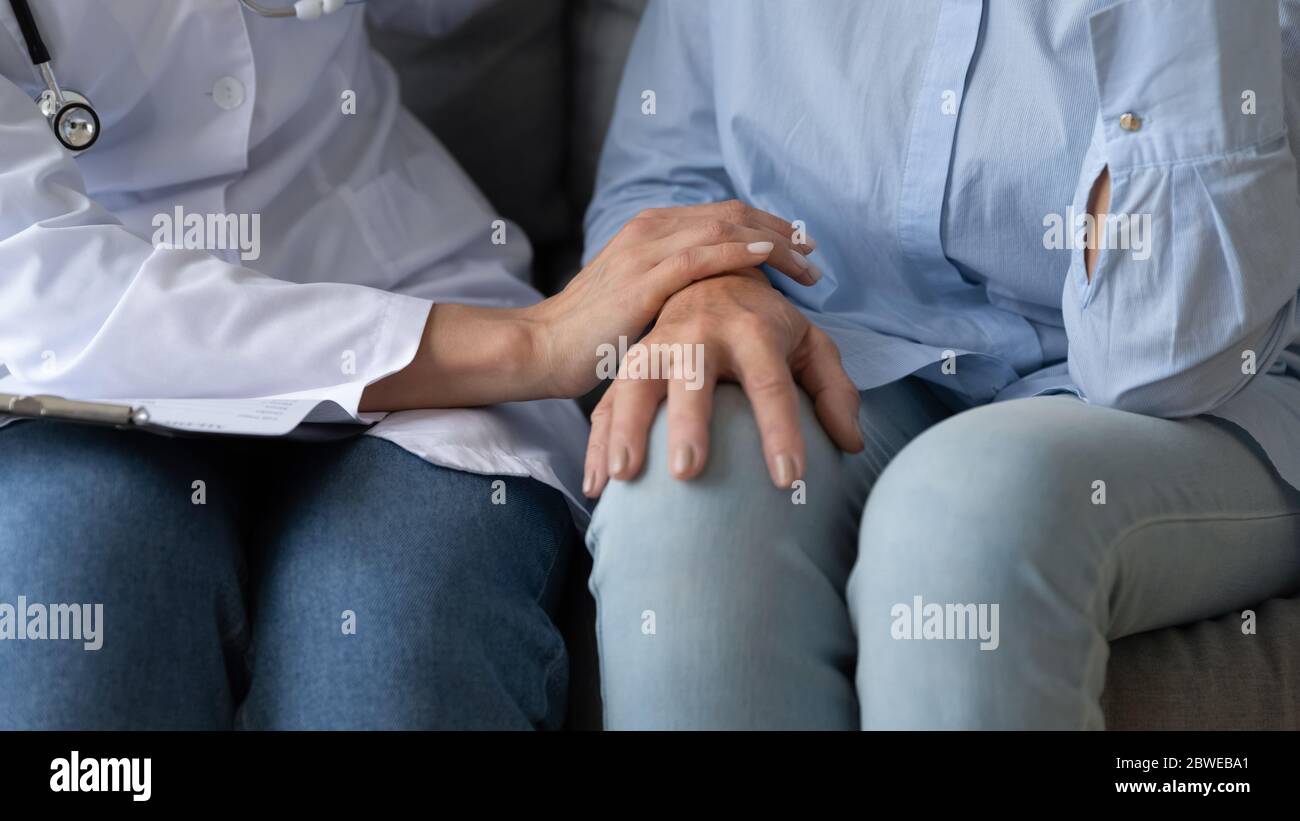 L'infermiere tocca la mano del paziente anziano esprime l'immagine di closeup empatia Foto Stock