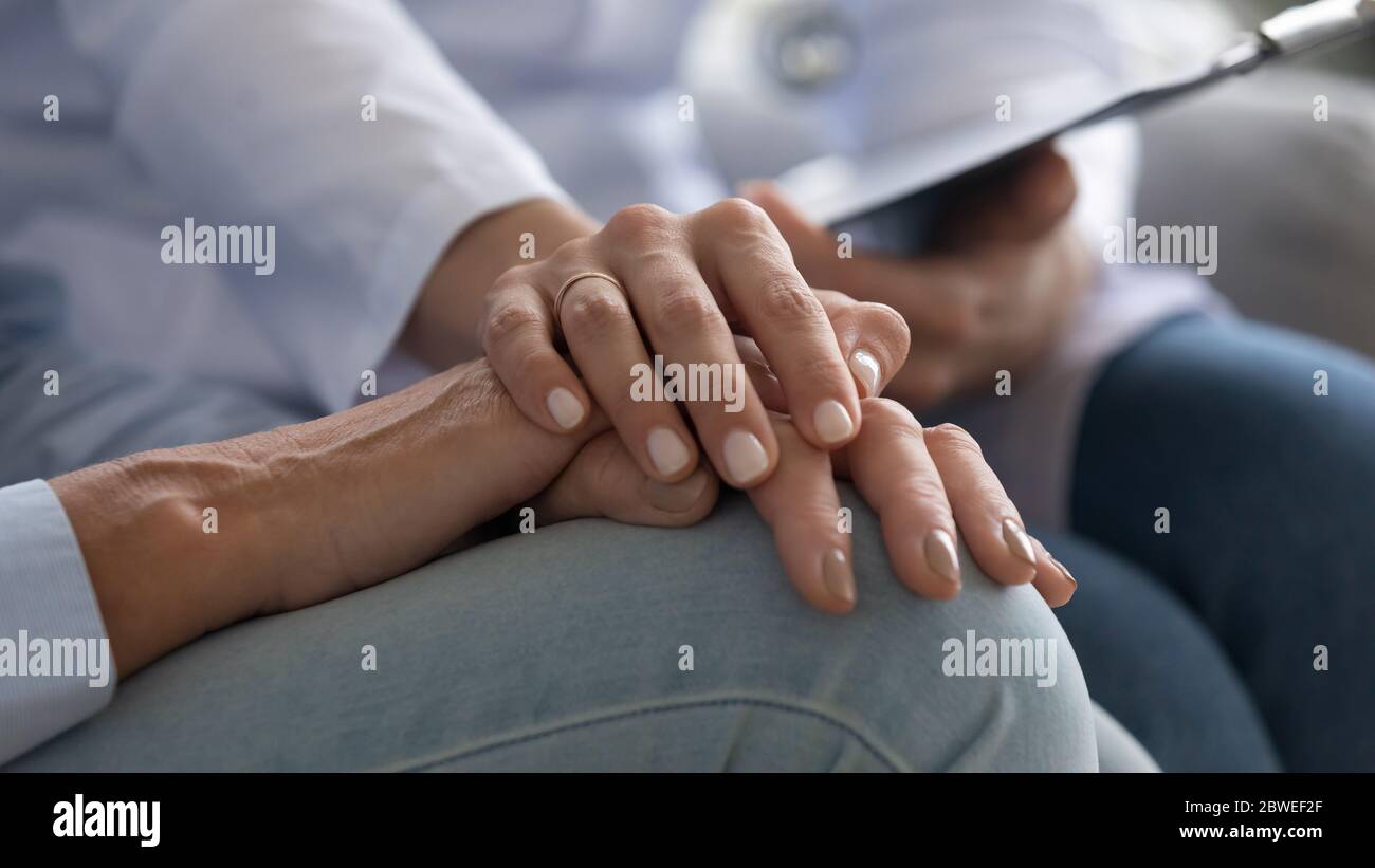 L'infermiere che tiene la mano di un paziente anziano fornisce un primo piano di supporto psicologico Foto Stock