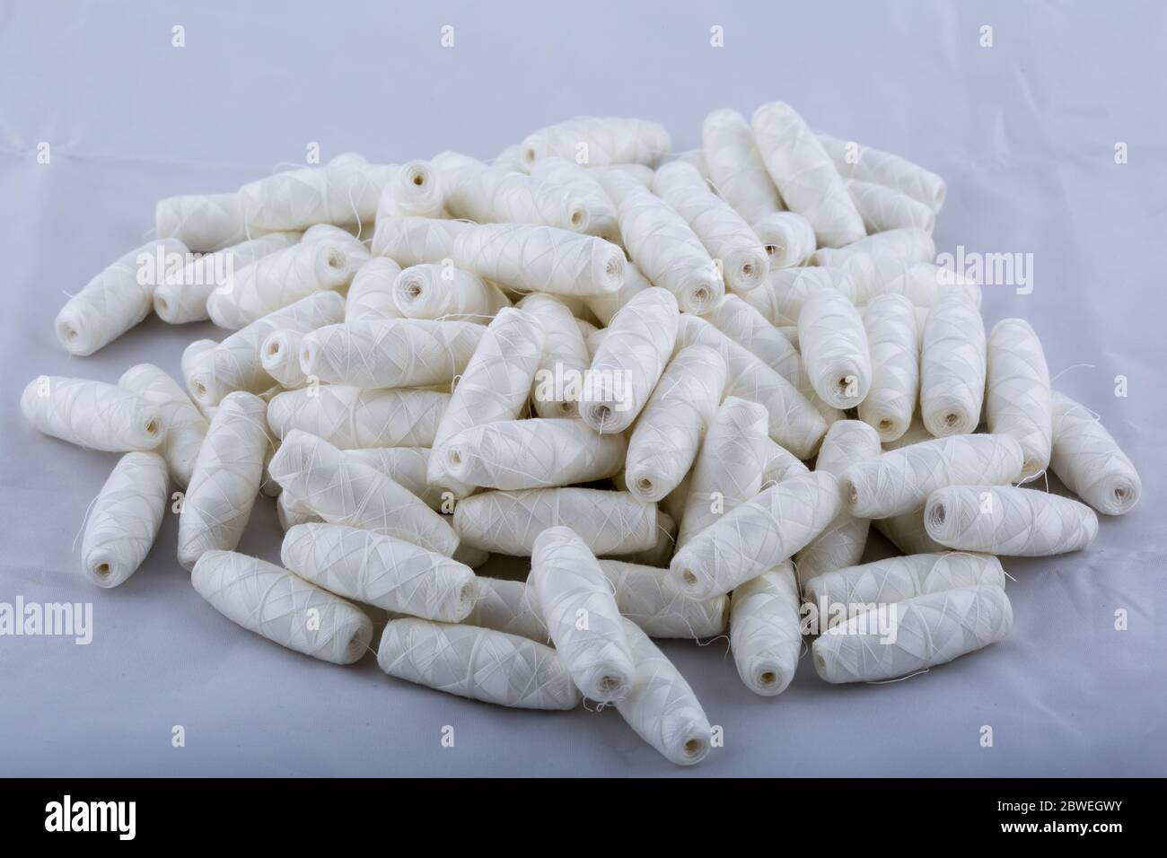 Un sacco di fili di cotone in bobine sparse sul tavolo. Materiali per cucire e per l'ago. Foto Stock