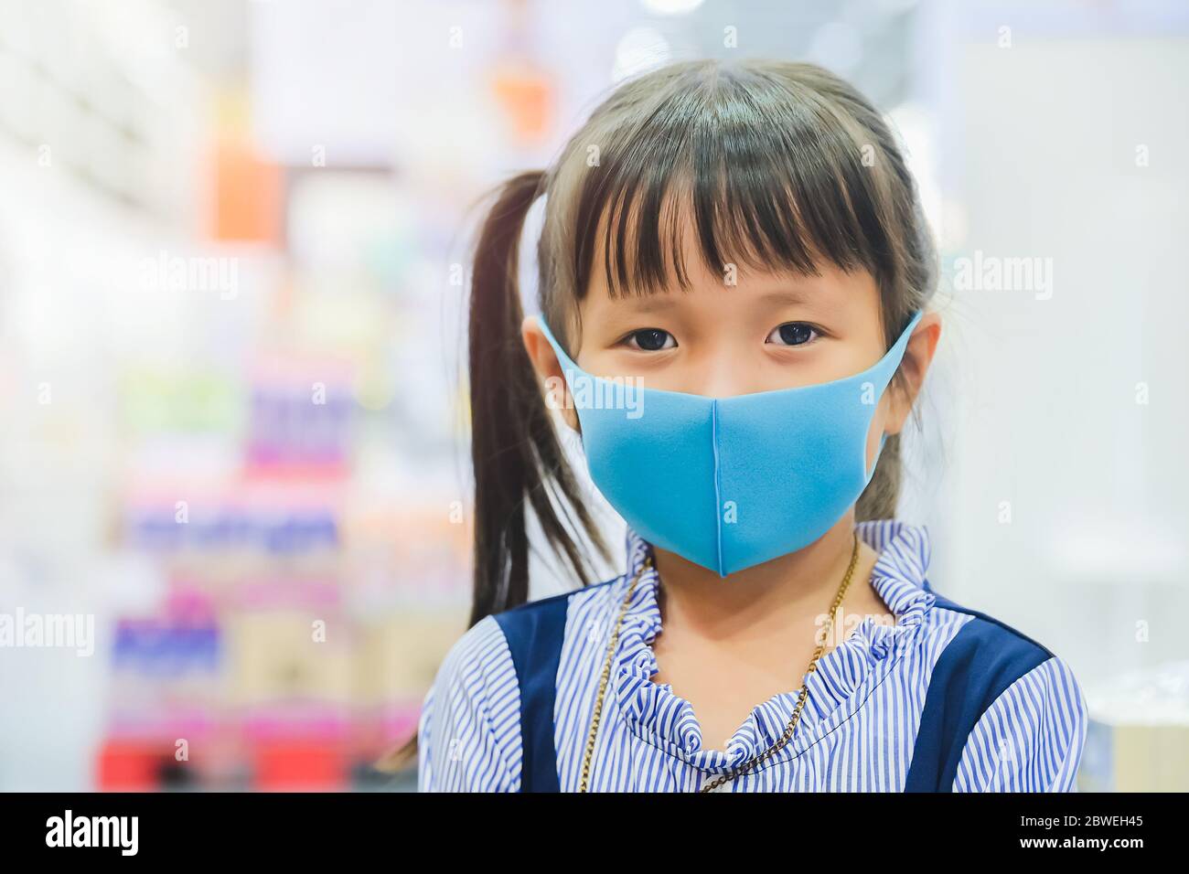 La bambina ha maschera di tessuto proteggersi da Coronavirus, nuovo stile di vita normale dopo COVID-19 epidemia bambino lasciare la casa con maschera sul naso per Foto Stock