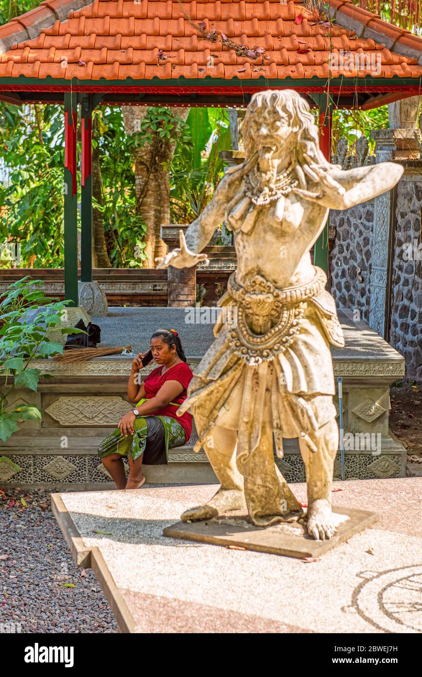 BALI, INDONESIA - 30 novembre 2019: Donna janitor che parla per telefono nel Palazzo dell'acqua di Tirta Gangga. Balinesi. Bali Est, Indonesia Foto Stock