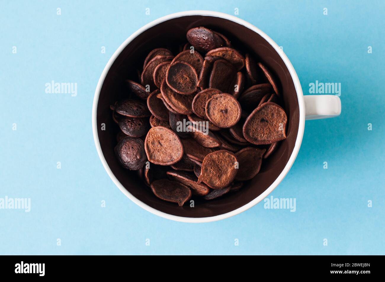 Cioccolata fatta in casa, minuscoli cereali pancake in una ciotola. Sfondo blu. Vista dall'alto. Foto Stock