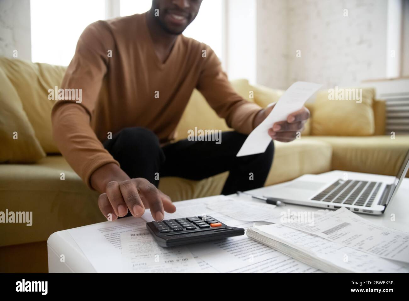Etnia africana uomo calcola le cifre utilizzando calcolatore pianificazione bilancio familiare Foto Stock