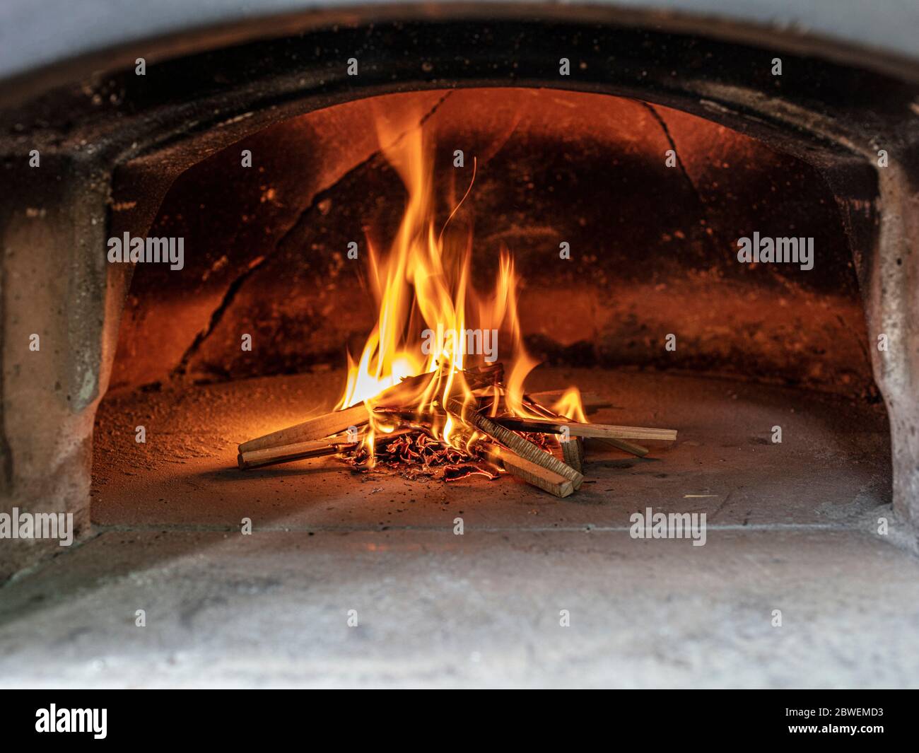 accendere il fuoco di un forno a legna per pizza. Foto Stock accendere il fuoco di un forno a legna per pizza. Foto Stock