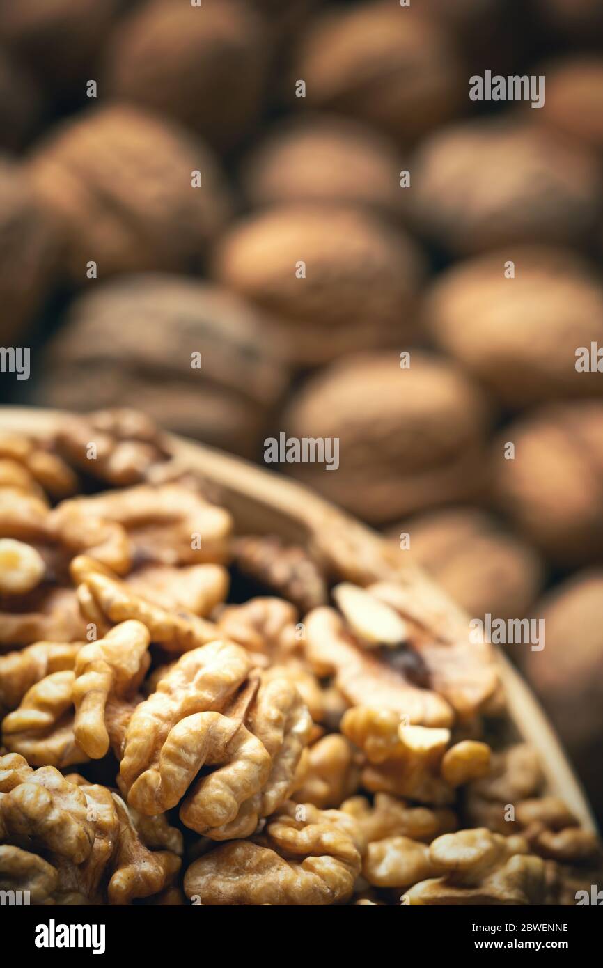 Noci fresche in una ciotola e noci intere sfocate sullo sfondo. Cibo biologico sano, viands BIO, sfondo naturale. Spazio per la copia per il tuo adv Foto Stock