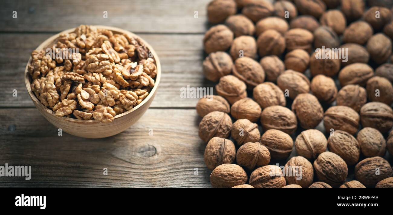 Noci fresche e noci intere in una ciotola su un tavolo rustico in legno. Cibo biologico sano, viands BIO, sfondo naturale. Spazio per la copia del Foto Stock