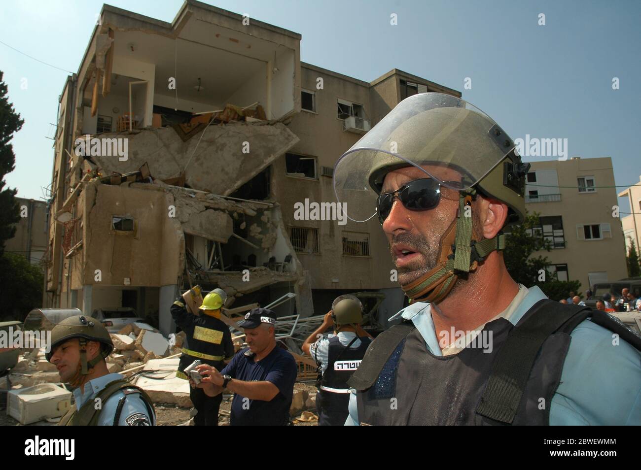 Il poliziotto israeliano ispeziona le macerie di un edificio residenziale distrutto dopo che ha subito un colpo diretto da un razzo Hezbollah Grad nel quartiere di Bat Galim nella città di Haifa durante la guerra Israele - Hezbollah Foto Stock