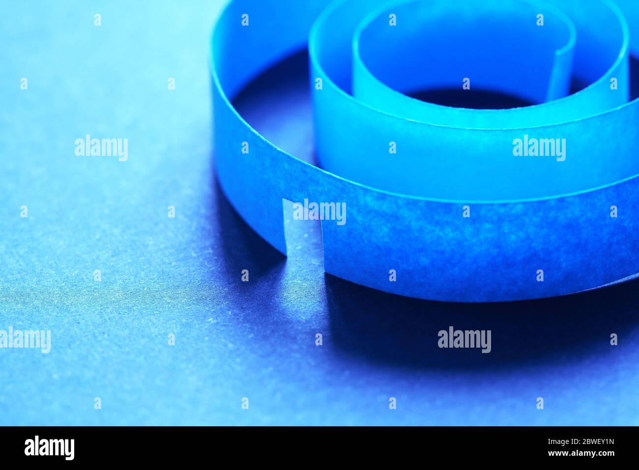 Concetto labirintico. Composizione astratta realizzata con spirale di carta su sfondo blu Foto Stock