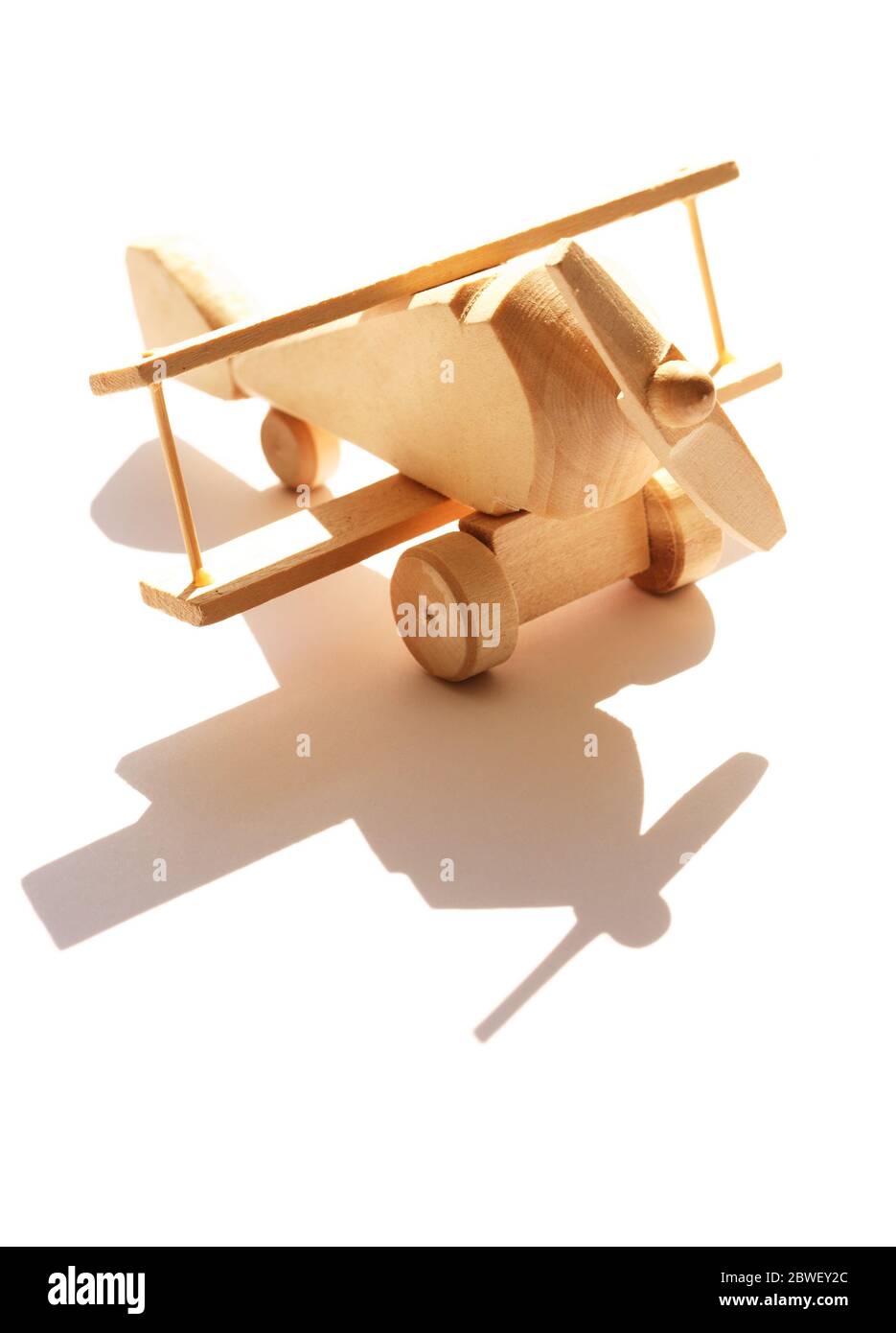 Concetto di viaggio. Piccolo aeroplano di legno contro la luce solare con ombra Foto Stock