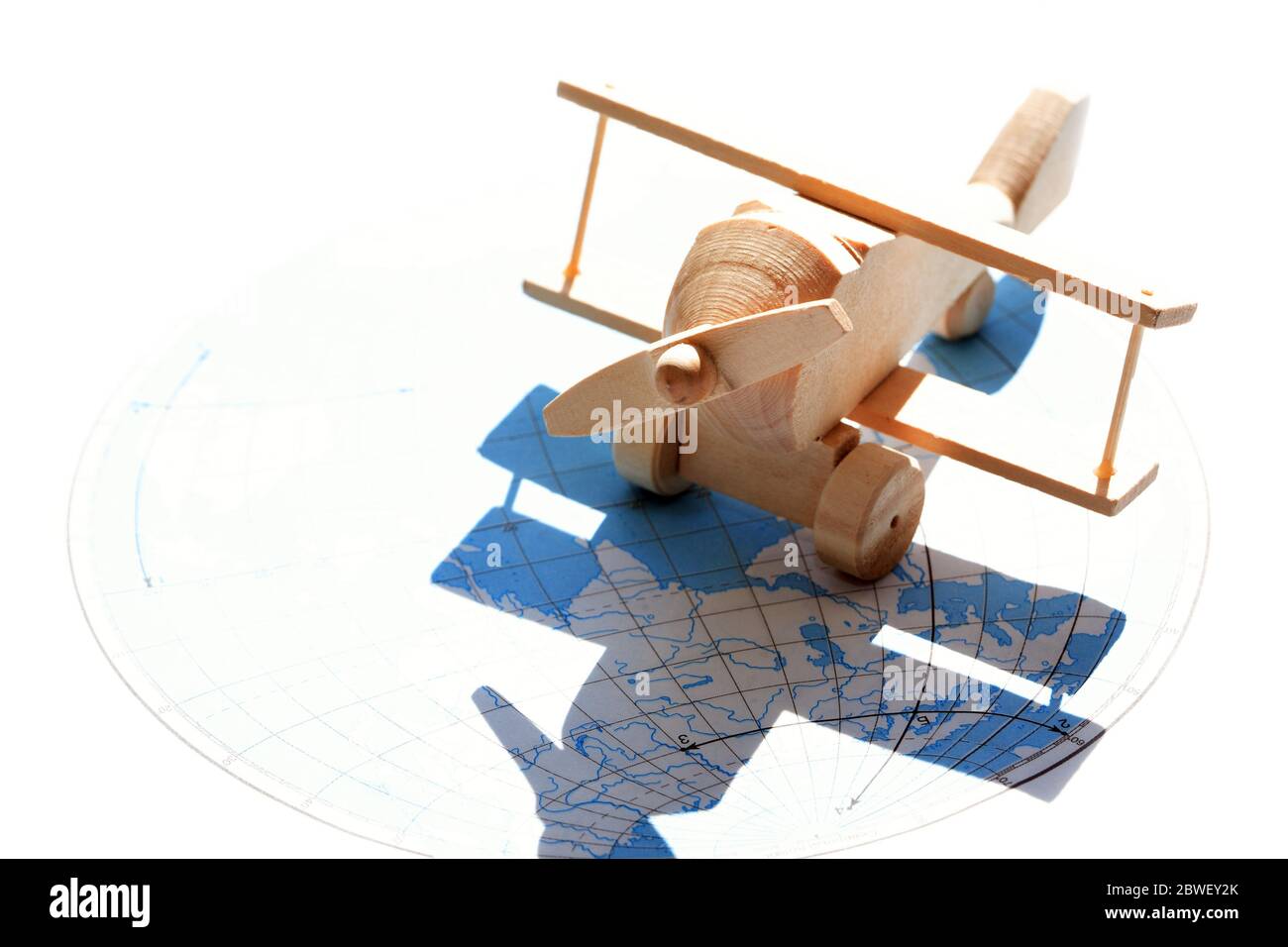 Concetto di viaggio. Piccolo aeroplano di legno contro la luce solare con mappa come ombra Foto Stock
