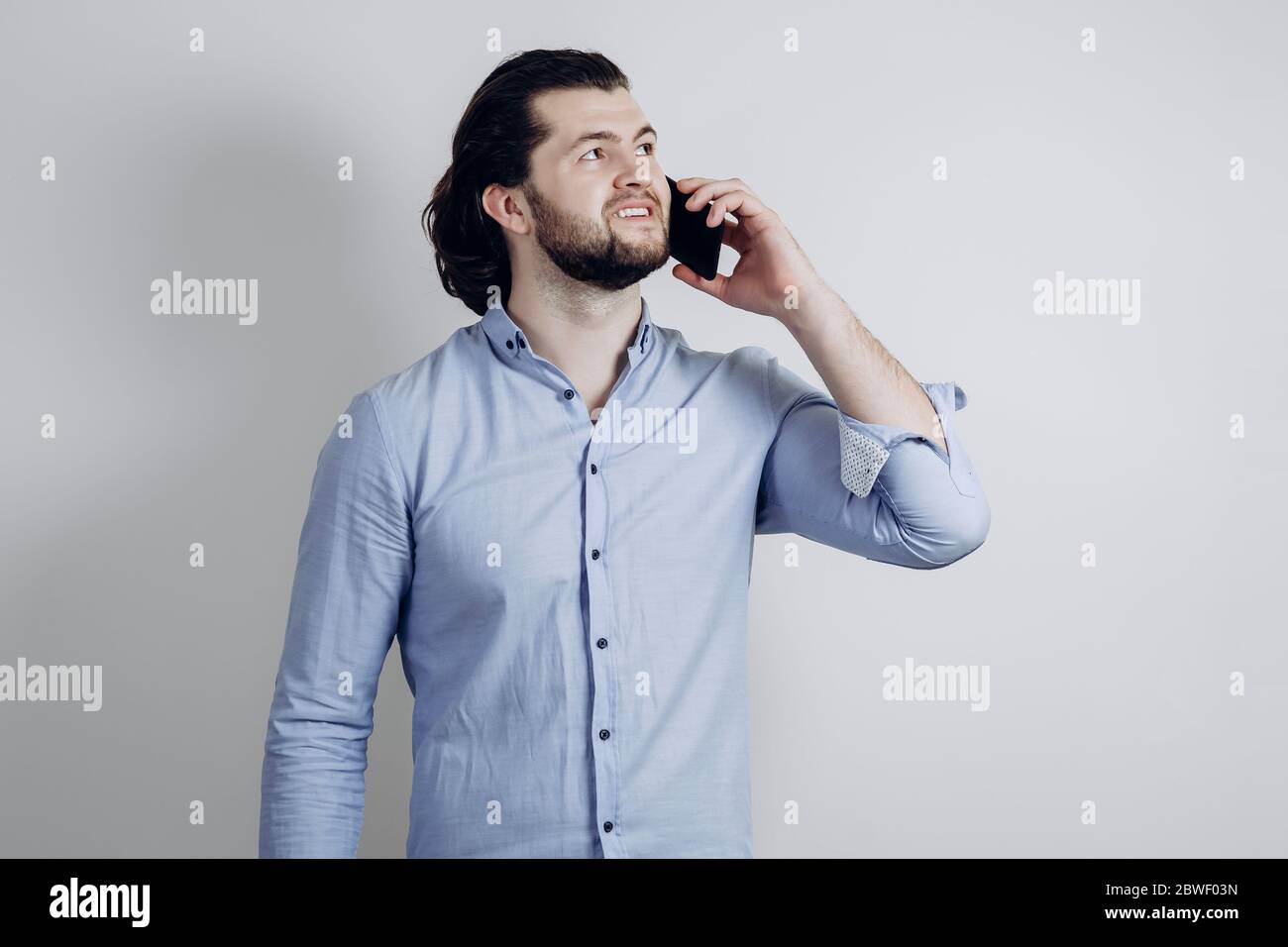 Uomo di successo in una camicia e con lunghi capelli che parlano al telefono Foto Stock