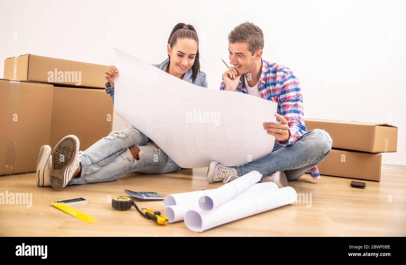 La coppia felice si è trasferita in una nuova casa che discute il disegno interno sopra i progetti. Foto Stock