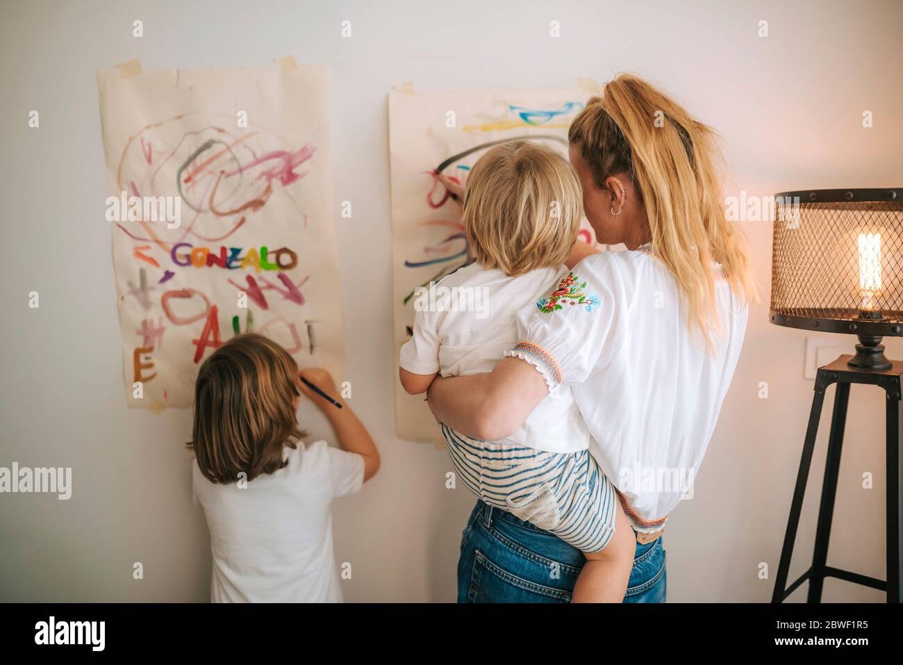 giovane madre con i suoi due bambini che dipingeva a casa. intrattenimento durante la quarantena. famiglia a casa. coronavirus. Foto Stock