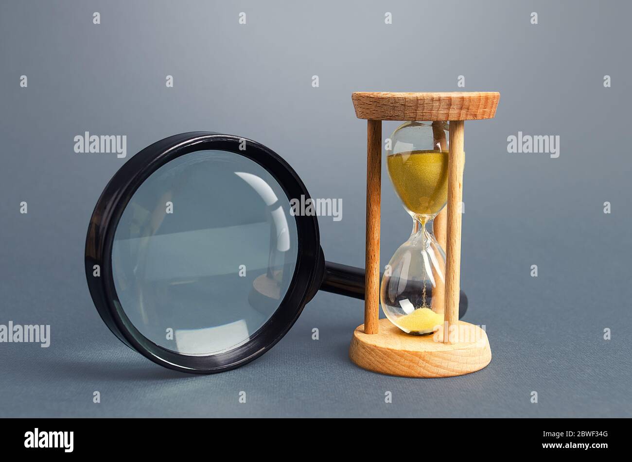 Lente di ingrandimento e clessidra. Concetto di ricerca limitata. Trova tempo libero. Abbonamento, piano a pagamento. Ricerca in breve tempo. Velocità ed efficienza. Scadenza Foto Stock