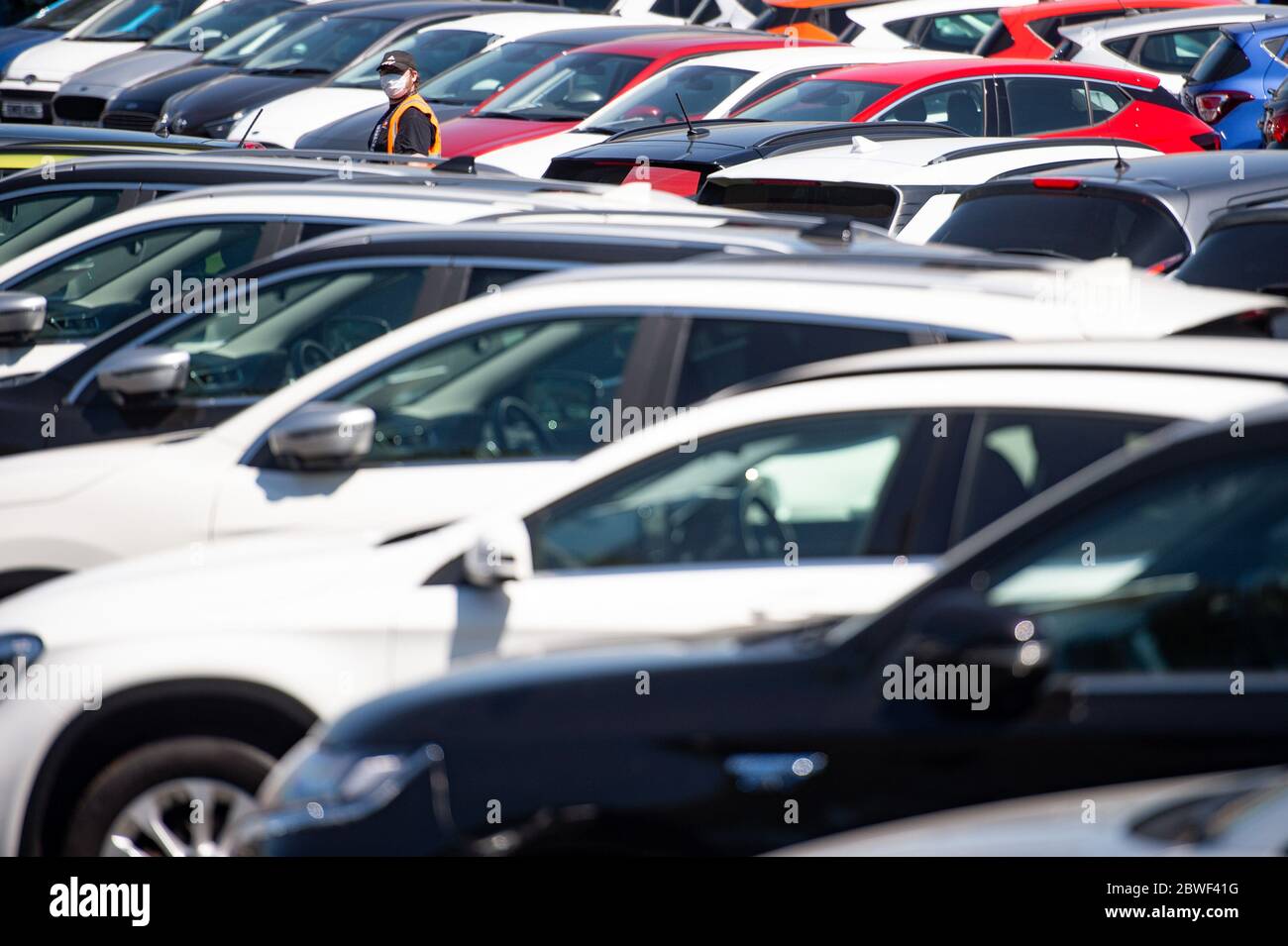 Un membro del personale che indossa una maschera protettiva sul piazzale dello showroom Motorpoint di Oldbury, West Midlands, mentre gli showroom delle auto aprono per la prima volta dal blocco, come parte di un più ampio allentamento delle restrizioni in Inghilterra. Foto Stock