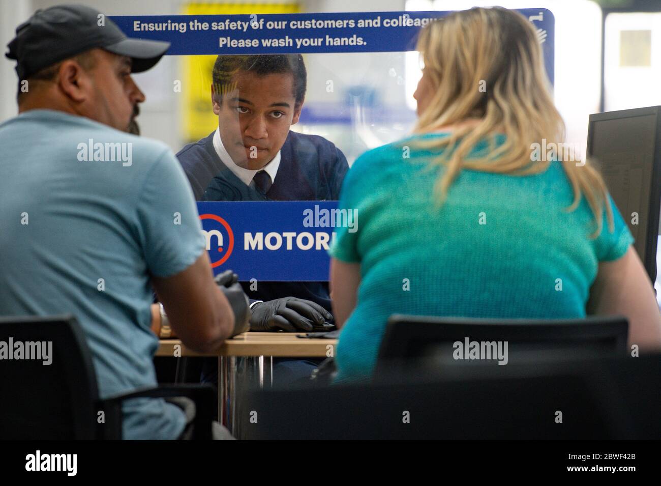 Un venditore di automobili parla con un cliente da dietro uno schermo protettivo presso lo showroom Motorpoint di Oldbury, West Midlands, mentre gli showroom delle auto si aprono per la prima volta dopo il blocco, come parte di un più ampio allentamento delle restrizioni in Inghilterra. Foto Stock