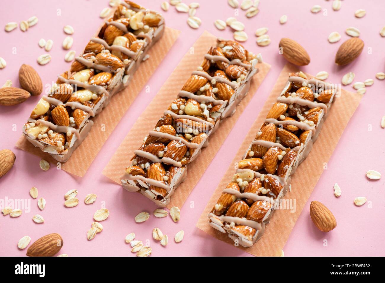 Barrette proteiche di Granola Almond su sfondo rosa. Minimalistico Fitness Food Still Life Foto Stock