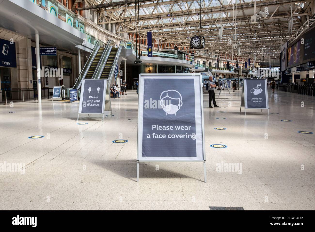 I cartelli di richiesta per l'igiene del lavaggio delle mani e la copertura del viso si trovano all'interno dell'atrio della stazione centrale di Waterloo, Londra, Inghilterra, Regno Unito Foto Stock